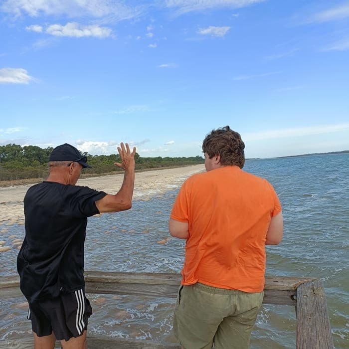 A support worker and participant looking out over the water